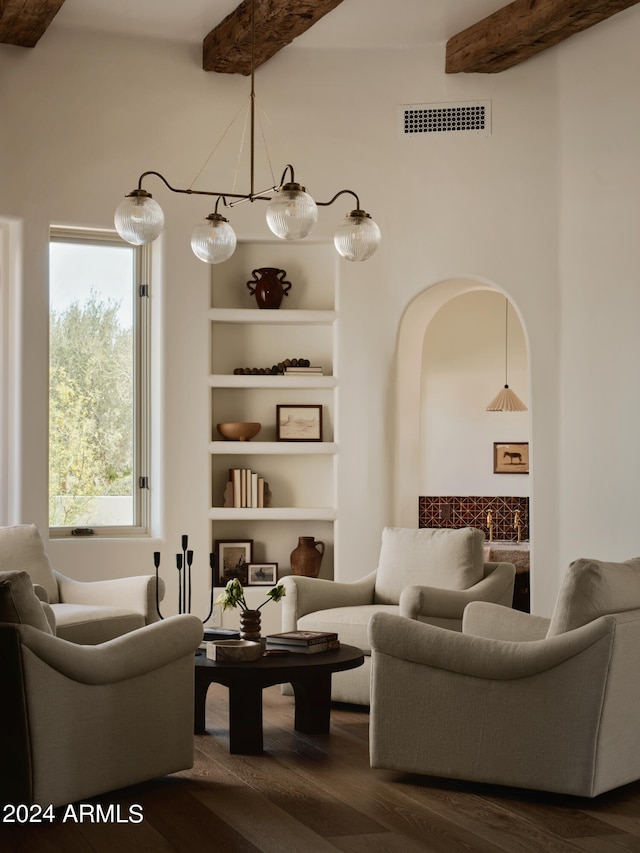 living area with a notable chandelier, hardwood / wood-style floors, built in features, and beam ceiling