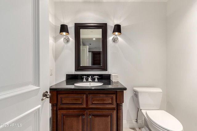 half bath with toilet, vanity, and baseboards