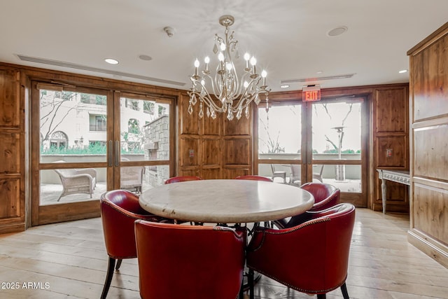 dining area with wood walls, french doors, and light wood-style floors