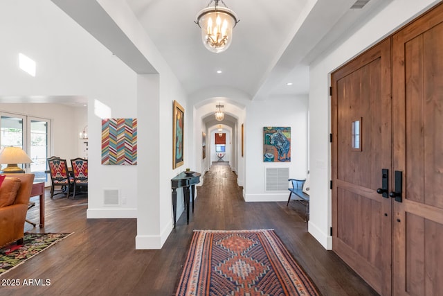 entryway with dark hardwood / wood-style floors and a notable chandelier