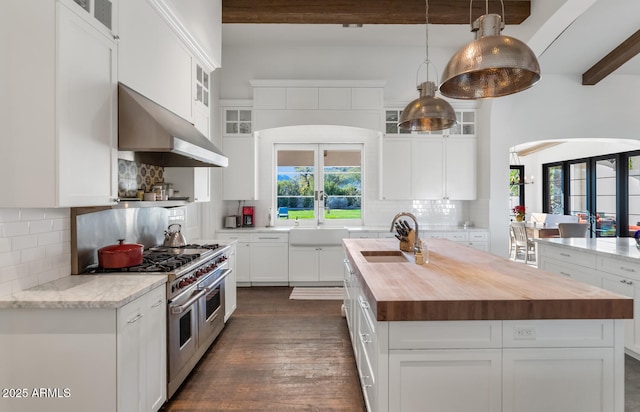 kitchen with double oven range, french doors, range hood, and a kitchen island