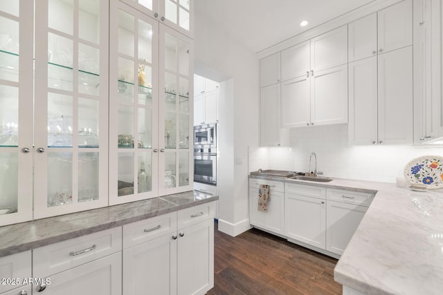 bar with stainless steel microwave, dark hardwood / wood-style floors, sink, white cabinets, and light stone counters