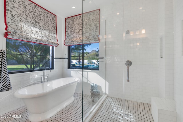 bathroom with plus walk in shower, tile patterned flooring, and tile walls