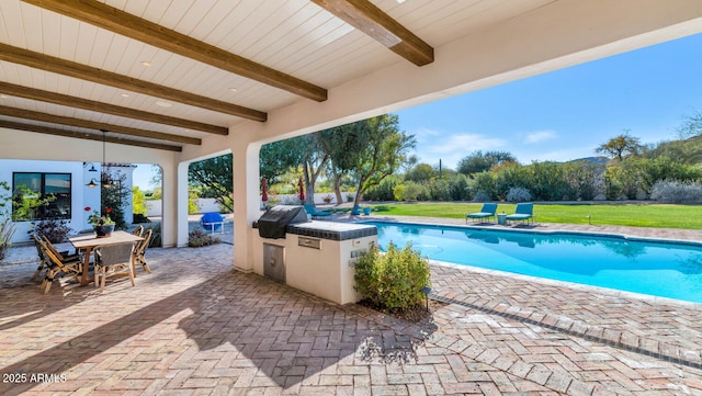 view of swimming pool featuring a lawn, an outdoor kitchen, a patio, and area for grilling