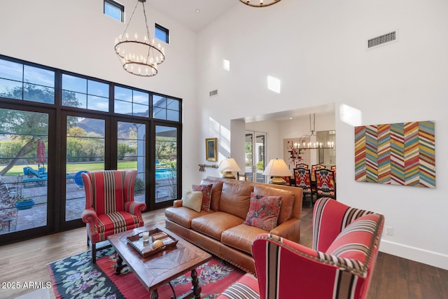 living room featuring a healthy amount of sunlight, a towering ceiling, and french doors