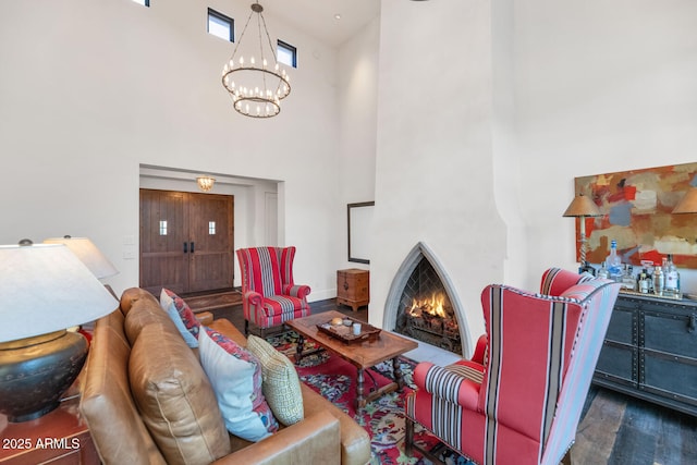 living room featuring a towering ceiling, dark hardwood / wood-style flooring, and an inviting chandelier