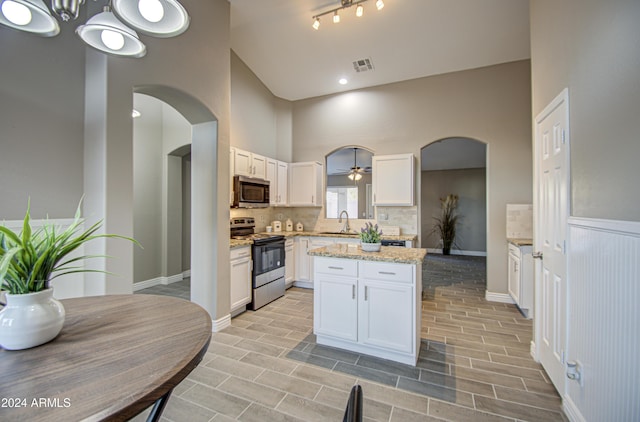 kitchen featuring appliances with stainless steel finishes, hanging light fixtures, and white cabinets