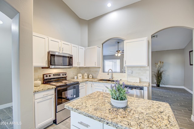 kitchen with sink, stainless steel appliances, white cabinetry, and light stone countertops