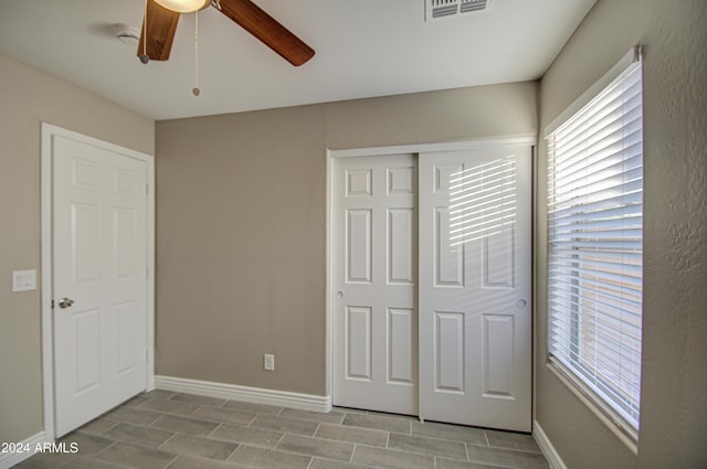 unfurnished bedroom with ceiling fan and a closet