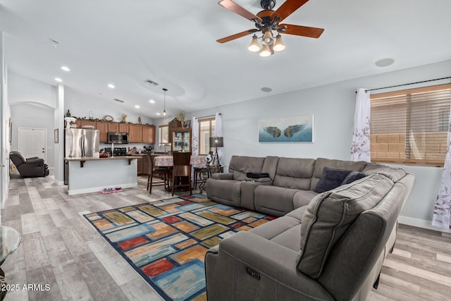 living room with ceiling fan, light hardwood / wood-style flooring, and vaulted ceiling