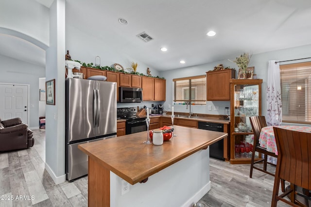 kitchen with a kitchen island, light hardwood / wood-style floors, vaulted ceiling, and appliances with stainless steel finishes