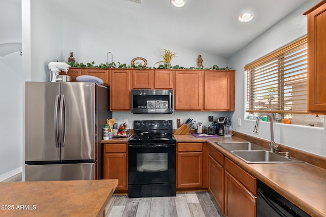 kitchen with sink, black appliances, vaulted ceiling, and light hardwood / wood-style flooring