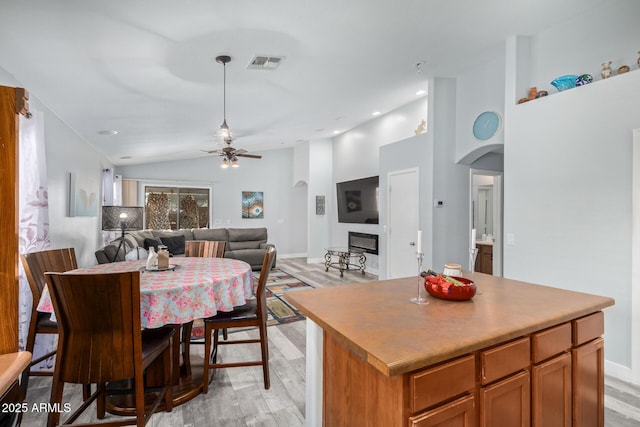 dining area featuring ceiling fan, light wood-type flooring, and lofted ceiling