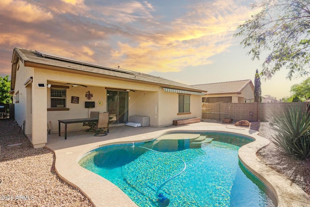 pool at dusk featuring a fenced in pool, a fenced backyard, ceiling fan, and a patio area