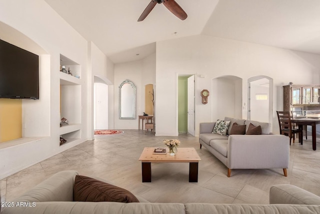 living area featuring arched walkways, a ceiling fan, built in shelves, and high vaulted ceiling