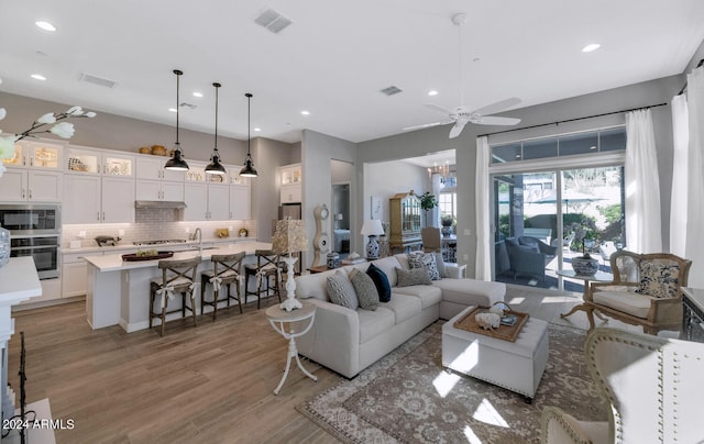 living room featuring ceiling fan, light wood-type flooring, and sink