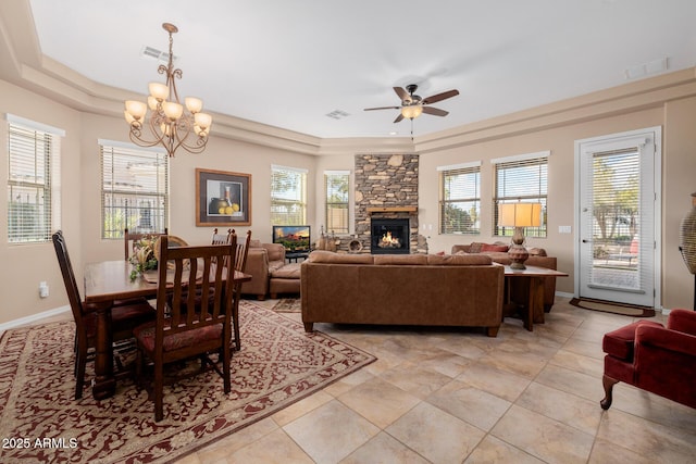 living room featuring a tray ceiling, a fireplace, light tile patterned flooring, and ceiling fan with notable chandelier