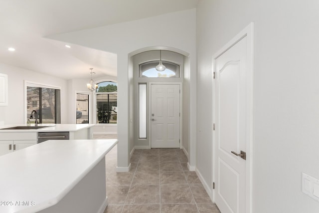 tiled foyer featuring an inviting chandelier and sink