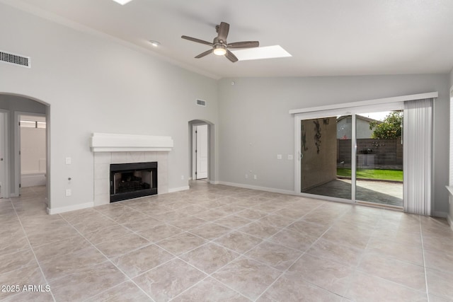 unfurnished living room with ceiling fan, lofted ceiling, light tile patterned floors, and a fireplace