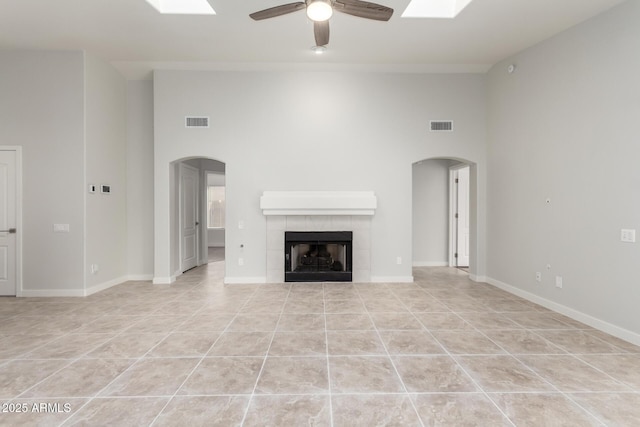 unfurnished living room featuring light tile patterned floors, a fireplace, ceiling fan, and a high ceiling