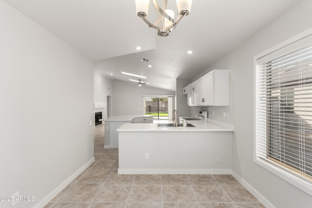 kitchen featuring white cabinetry, stove, ceiling fan with notable chandelier, vaulted ceiling, and kitchen peninsula