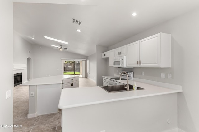 kitchen featuring white cabinetry, a center island, ceiling fan, kitchen peninsula, and white appliances