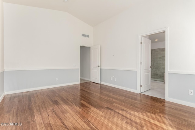 empty room with hardwood / wood-style floors and vaulted ceiling