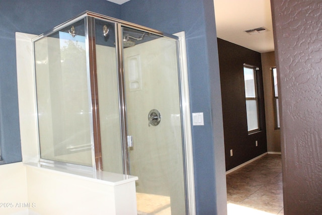 bathroom with an enclosed shower and tile patterned floors