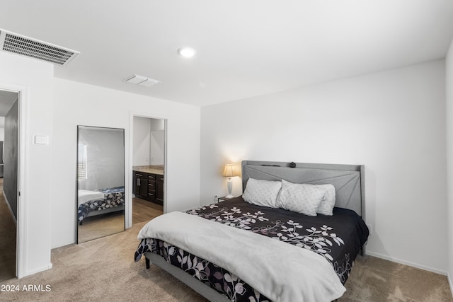 bedroom featuring ensuite bath and carpet flooring