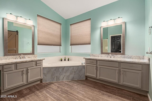 3946 N 112th Ave, Avondale, AZ 85392 - full bathroom with wood finished floors, two vanities, vaulted ceiling, and a garden tub