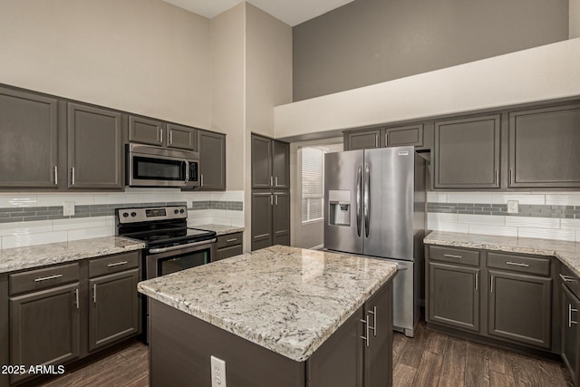 3946 N 112th Ave, Avondale, AZ 85392 - kitchen featuring stainless steel appliances, decorative backsplash, a towering ceiling, and light stone counters