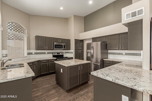 3946 N 112th Ave, Avondale, AZ 85392 - kitchen featuring appliances with stainless steel finishes, a sink, light stone countertops, a high ceiling, and tasteful backsplash