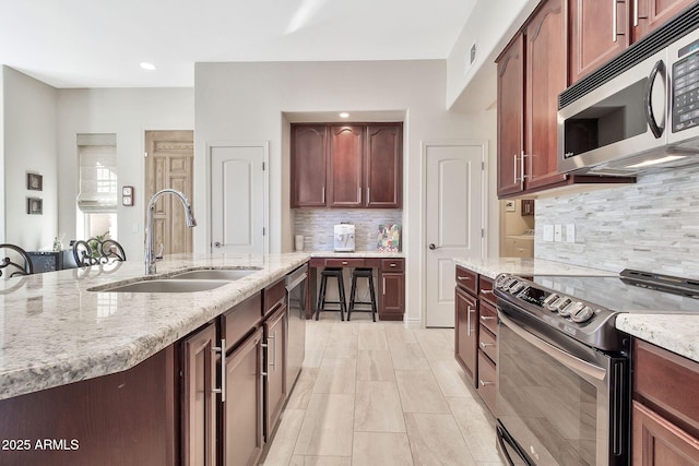 kitchen with light stone countertops, sink, backsplash, and stainless steel appliances