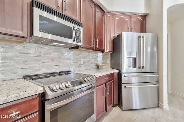 kitchen featuring tasteful backsplash, light tile patterned floors, light stone countertops, and stainless steel appliances