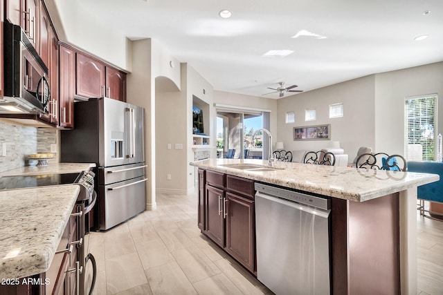 kitchen with sink, stainless steel appliances, a center island with sink, and backsplash