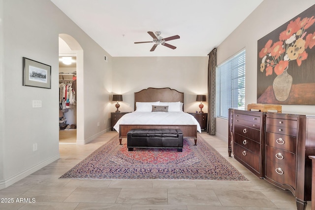 bedroom featuring ceiling fan, light hardwood / wood-style floors, a closet, and a walk in closet