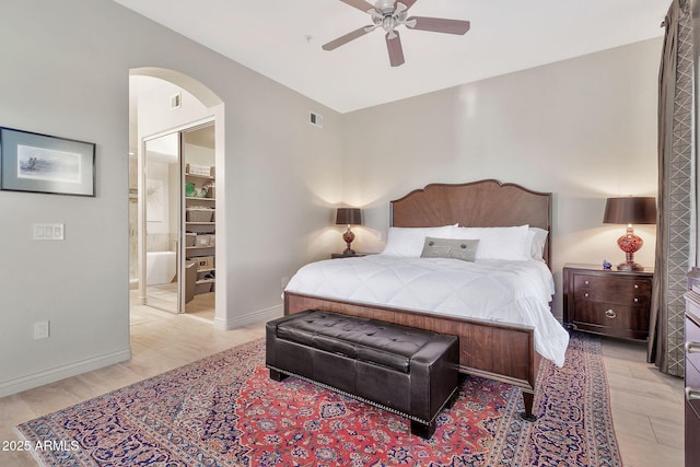 bedroom featuring light hardwood / wood-style floors, ensuite bath, and ceiling fan