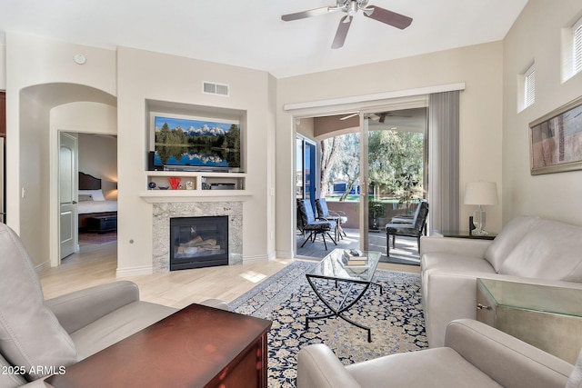 living room with ceiling fan, wood-type flooring, and a high end fireplace