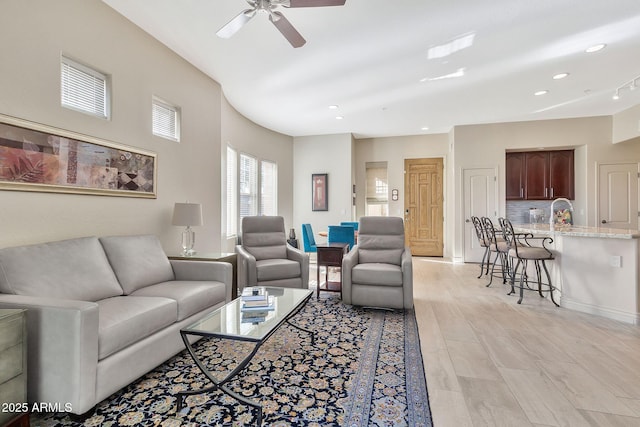 living room featuring sink, light hardwood / wood-style flooring, and ceiling fan