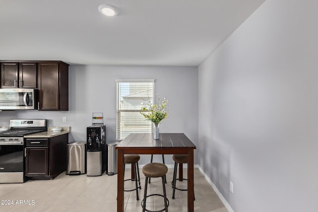 3929 S 79th Ln, Phoenix, AZ 85043 - kitchen with light tile patterned floors, dark brown cabinets, appliances with stainless steel finishes, light countertops, and baseboards