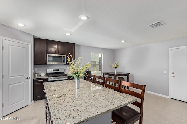 3929 S 79th Ln, Phoenix, AZ 85043 - kitchen with visible vents, a center island, dark brown cabinetry, stainless steel appliances, and a breakfast bar area