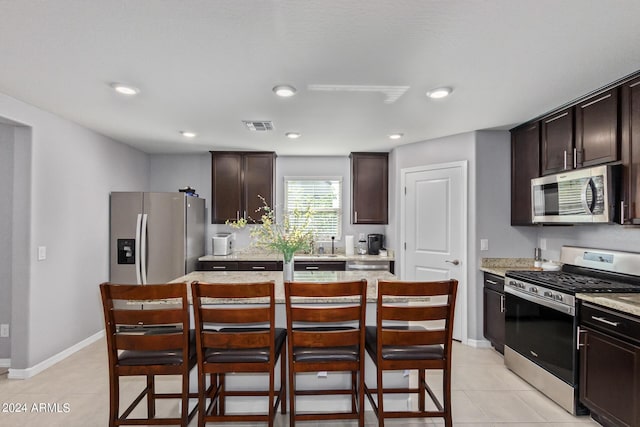 3929 S 79th Ln, Phoenix, AZ 85043 - kitchen with dark brown cabinets, a kitchen island, visible vents, a breakfast bar area, and appliances with stainless steel finishes