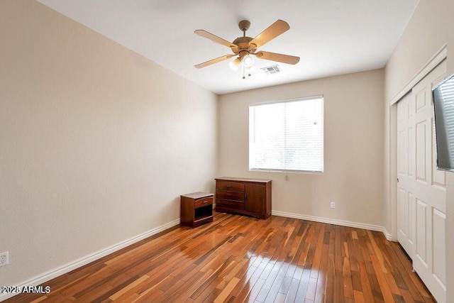 unfurnished bedroom featuring hardwood / wood-style floors, a closet, and ceiling fan