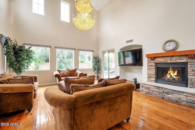 living room featuring a stone fireplace, hardwood / wood-style floors, and a notable chandelier