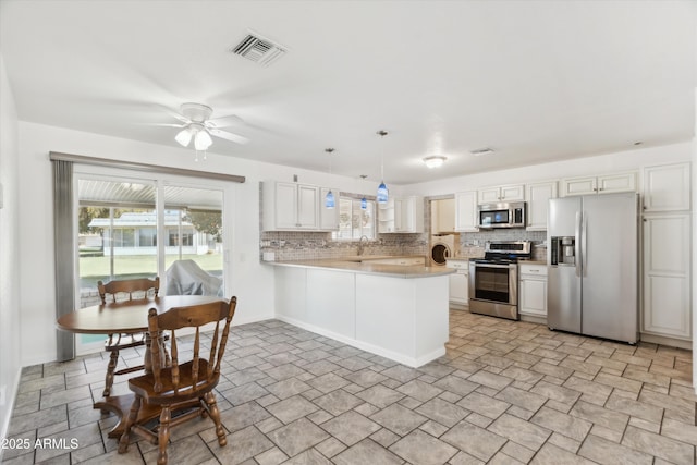 kitchen featuring stainless steel appliances, white cabinetry, kitchen peninsula, and hanging light fixtures