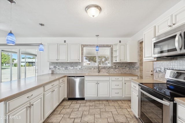 kitchen with decorative light fixtures, sink, appliances with stainless steel finishes, and white cabinetry