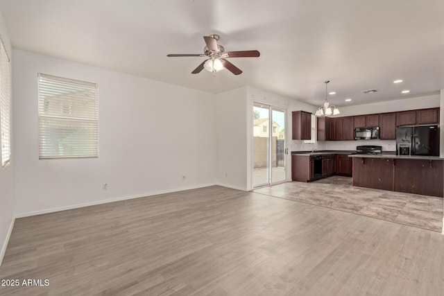 kitchen featuring light hardwood / wood-style flooring, hanging light fixtures, dark brown cabinets, black appliances, and ceiling fan with notable chandelier