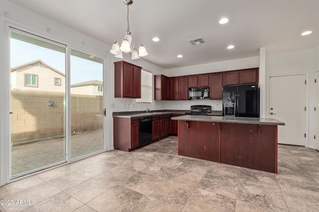 kitchen featuring sink, a center island, black appliances, a kitchen bar, and decorative light fixtures