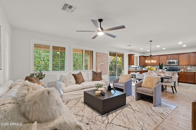 living room featuring ceiling fan with notable chandelier, light hardwood / wood-style flooring, and sink