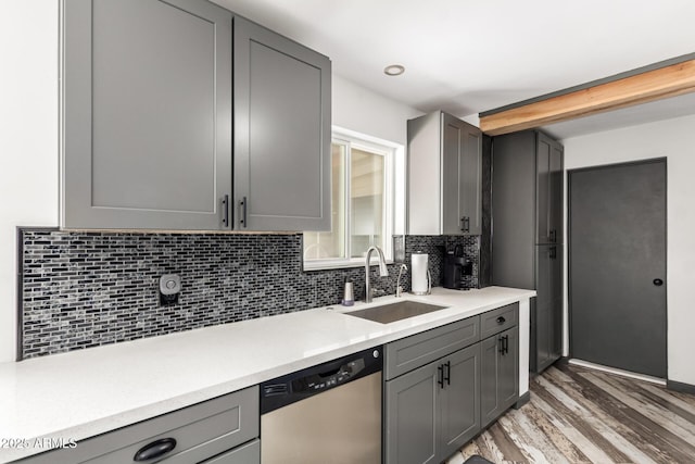 kitchen featuring tasteful backsplash, dishwasher, sink, and gray cabinetry